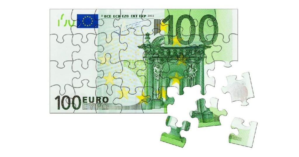 Ein Hundert-Euro-Schein als Puzzle, an der unteren rechten Ecke sind vier Puzzleteile herausgetrennt | Immobilienfinanzierung